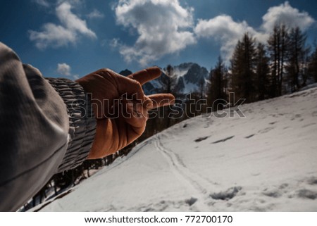 Man's hand shows magic winter landscape Monte Lussari, Italy