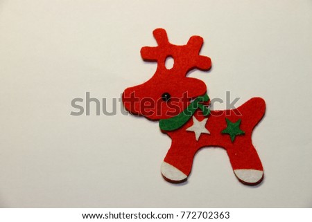 A handicraft for Christmas, a red fabric deer with a green scarf and a white and a green star decoration at the right part of the screen.