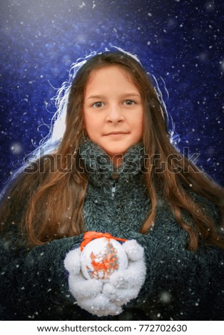 Beautiful young girl holding Christmas ornament.