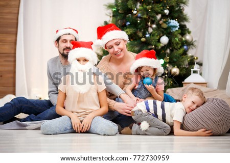 Photo of happy family in Santa caps at Christmas tree