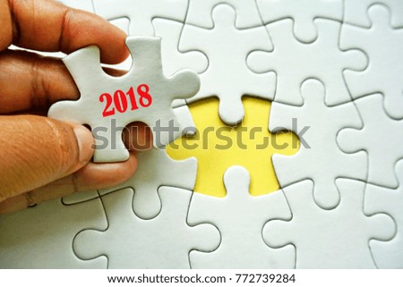 A hand holding a piece of puzzle with a words 2018. Conceptual image for incoming new year 2018.