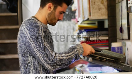 Side view of man working as photocopier and copying papers with machine. 