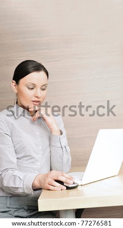 Portrait of a beautiful young businesswoman on the computer, hand on chin. Office background.