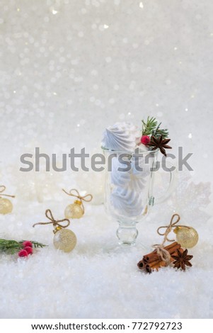 Closeup of mini meringues cookies in a glass jar on white background. Christmas or new year card