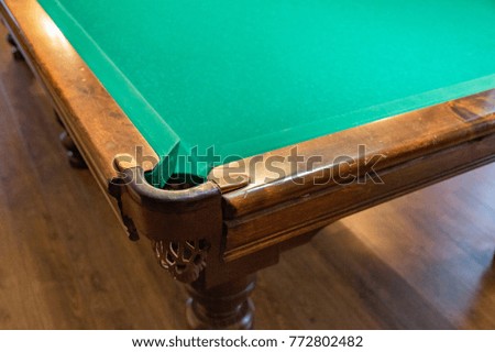 Large wooden table with green cloth for playing billiards