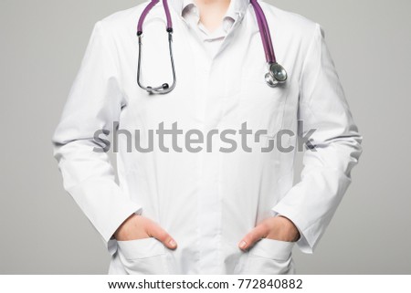 a doctor in a white coat put hands in pockets close-up isolated on white background