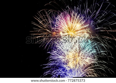 Colorful, beautiful fireworks on the night sky over the city. New Year celebration. Blurry, falling stars. 