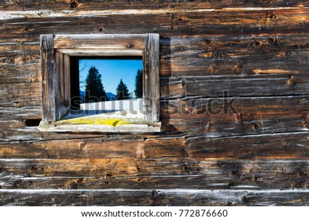 Vintage window of old wooden cabin mirrors winter mountain landscape. Wooden rustic background.