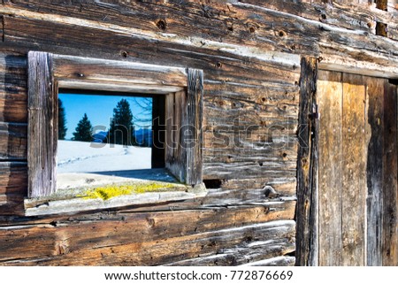 Vintage window and door of old wooden cabin mirrors winter mountain landscape. Wooden rustic background.