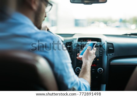 man using phone while driving the car Royalty-Free Stock Photo #772891498