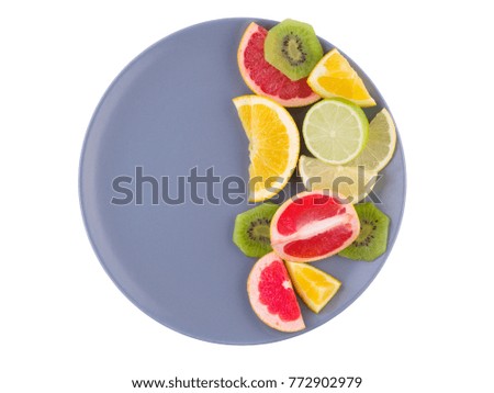 Tropical fruit fills the right half of a plate on a white isolated background. View from above