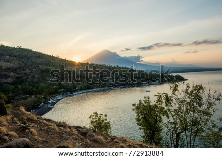 Sunset over the picturesque ocean bay with a mountain on horizon