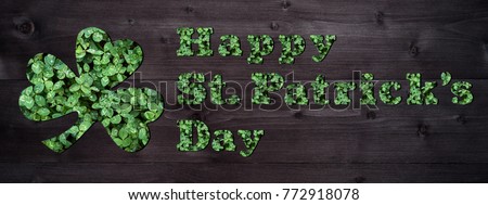 Happy St. Patricks day sign made from green leaves of clover shamrock on dark wooden background. Happy St. Patrick's day banner lettering, greeting card, March 17