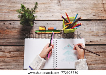 Preparing for the Christmas holidays. girl writing a letter to santa, wooden background, top view of copy space, female hands in picture
