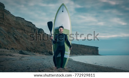 Portrait of a young male surfer in a wetsuit on the beach.