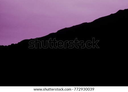 Purple outline of black mountains. Magnificent natural scenery. View of the horizon. Background, texture, pattern, wallpaper