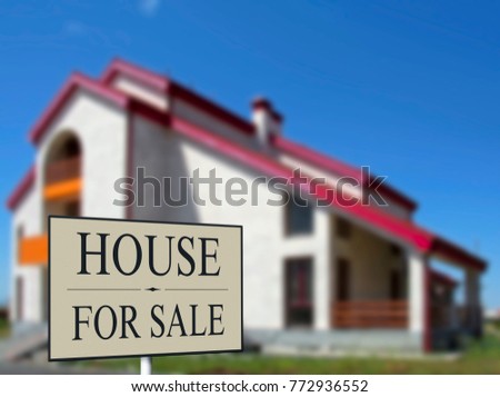 Home For Sale Real Estate Sign in Front of Beautiful New House. Blurred background