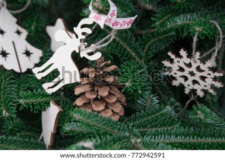A Christmas or New Year background of a natural fir tree with wooden toys and a natural pine cone. Close up
