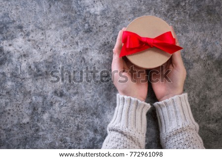 Female hands holding present with bow on rustic background. Festive backdrop for holidays: Birthday, Valentines day, Christmas, New Year. Flat lay style