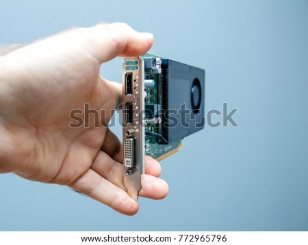 Man holding against gray background powerful GPU video card  used in professional video production in bitcoin cryptocurrency mining