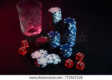 Poker chips and wine glass of cognac on dark table. Gambling