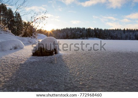 Wintry landscape scenery from Finland. Image taken from low point of view. Snowy lake ice. Sunrise, cold morning.