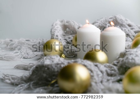 White holiday candles by silver toy, Happy New Year and knitted plaid rustic wooden background; holiday background with white copy space