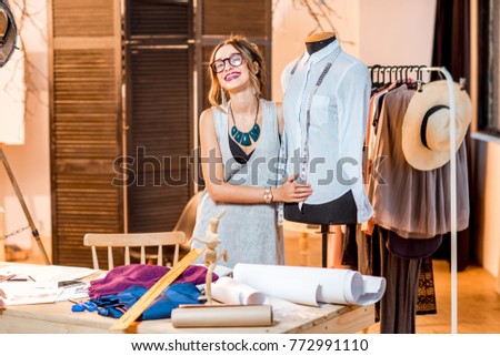 Portrait of a young fashion designer with mannequin at the studio with different tailoring tools
