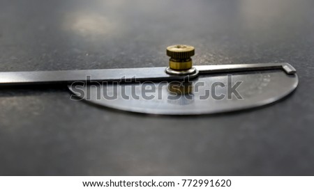 Protractor angle finder stainless steel over black granite table (closeup view and selective focus)