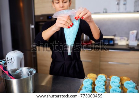 The confectioner with a pipping bag of cream in his hands in the Royalty-Free Stock Photo #773000455