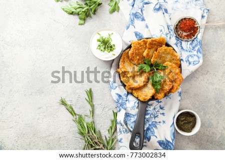 Potato latkes traditional jewish pancakes with sour cream, parsley, dry red pepper flakes and mint sauce. Background, white napkin with blue flowers. Hannukah celebration dish concept. Copy space.