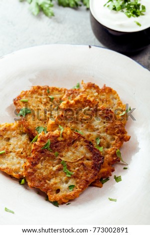 Potato latkes traditional jewish pancakes with sour cream, parsley, dry red pepper flakes and mint sauce. Background, white napkin with blue flowers. Hannukah celebration dish concept.