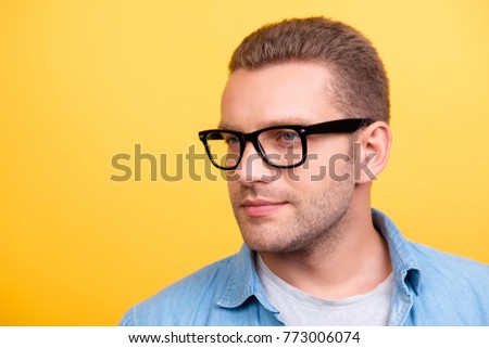 Close up portrait of bearded man in glasses with serious expression looking to the side over yellow background
