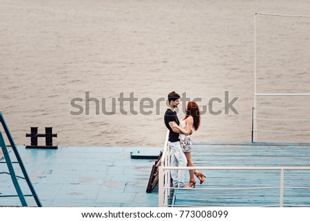 Love story of the beautiful young man and woman. embrace on a city walk. embrace on the pier. background of water from afar