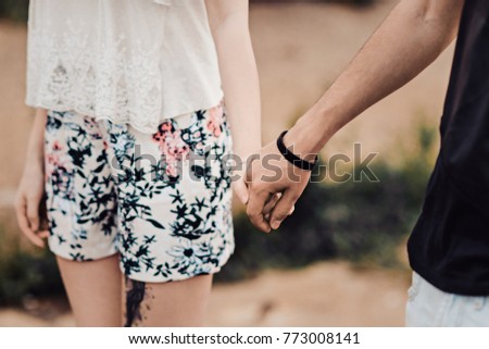 Love story of the beautiful young man and woman. embrace on a city walk. walking along the quay holding hands closeup