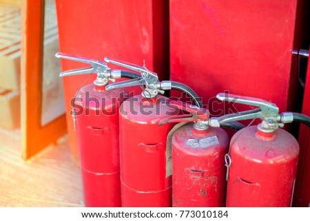 Old fire extinguishers with red fire hose background. Close up group of red fire extinguishers tank available in fire emergencies. Protection and security concepts. - Selective focus.