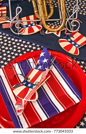 patriotic table setting with stars and stripes pattern on red plate and musical instrument