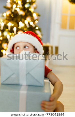 New Year's photo of boy in Santa's cap with gift box on background