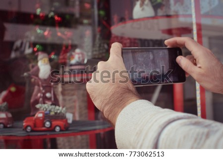 Close up on buyer hands using mobile phone choosing selecting purchase, taking picture of display window. Back side view photography of adult man tourist street shopping