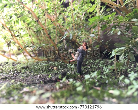 Loving couple concept - A happy couple hugging from miniature action figure with garden background.