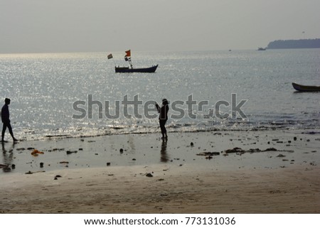 Girl taking picture of a boy on the beach