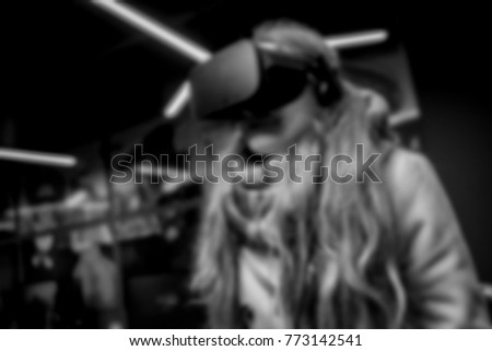 The girl in glasses of a virtual reality. Blurred image. A struck young woman touches the air during the VR experience. A young woman uses a virtual reality headset. Soft focus. black and white photo