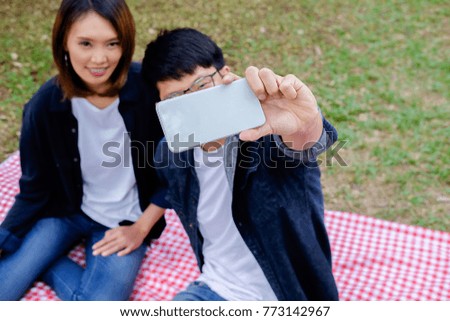 Happy young asian friends having fun on the picnic, making selfie with smartphone.  Picnic concept.