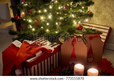  Gifts and candles under the decorated  christmas tree in red colours.                          