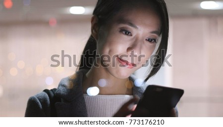 Woman sending sms on cellphone at night 