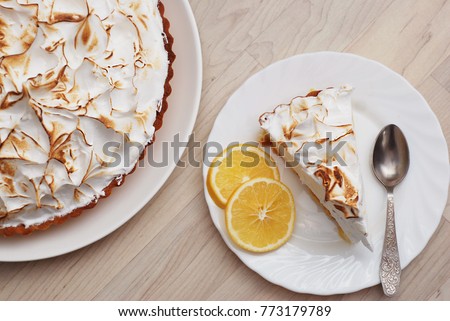 Piece of Lemon Meringue Pie on White Plate with Lemon Sliced on Wooden background