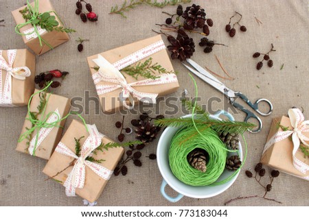 Cristmas presents geeving theme. Cute gift boxes decorated with festive ribbons and branches of natural evergreen plants on rough textured background. Handmade Xmas decor. Happy winter holiday theme