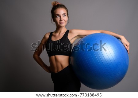 Studio shot of young beautiful woman ready for gym against gray background