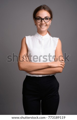 Studio shot of young beautiful businesswoman against gray background