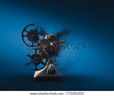 Old film projector exploding on a blue background